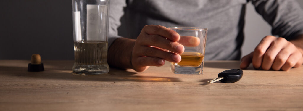 ruka-drzi-pohar-alkoholu-na-stole-vedla-klucov-od-auta